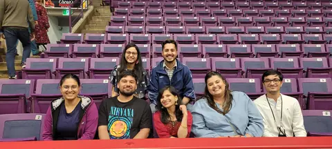 The team posing together in arena seats