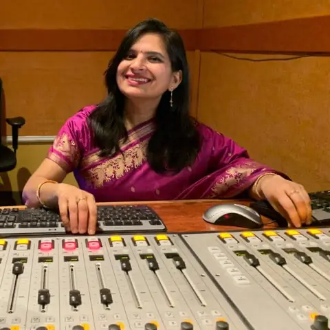 Swati at the mixing desk in a pink and gold outfit
