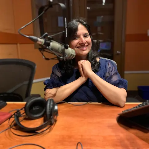 Swati smiling at the studio microphone with headphones on the desk
