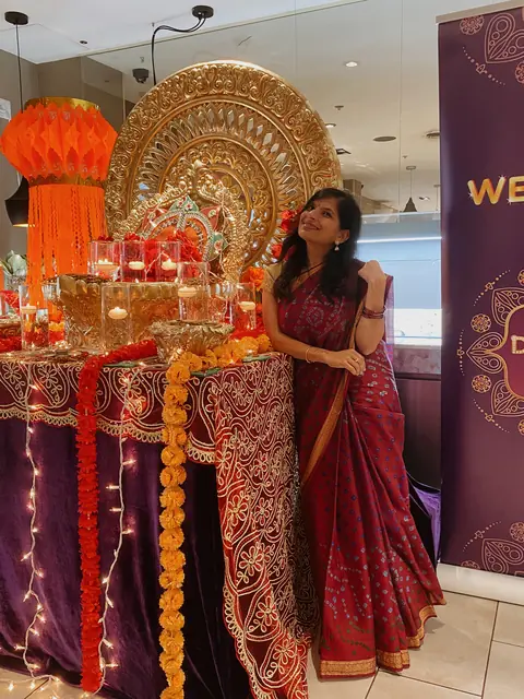 Swati in a red sari beside a decorated festive stage
